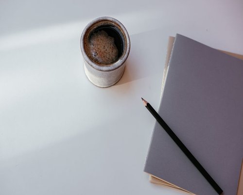 A clean workspace desk with notebooks, pencils, and a cup of traditional Mexican coffee